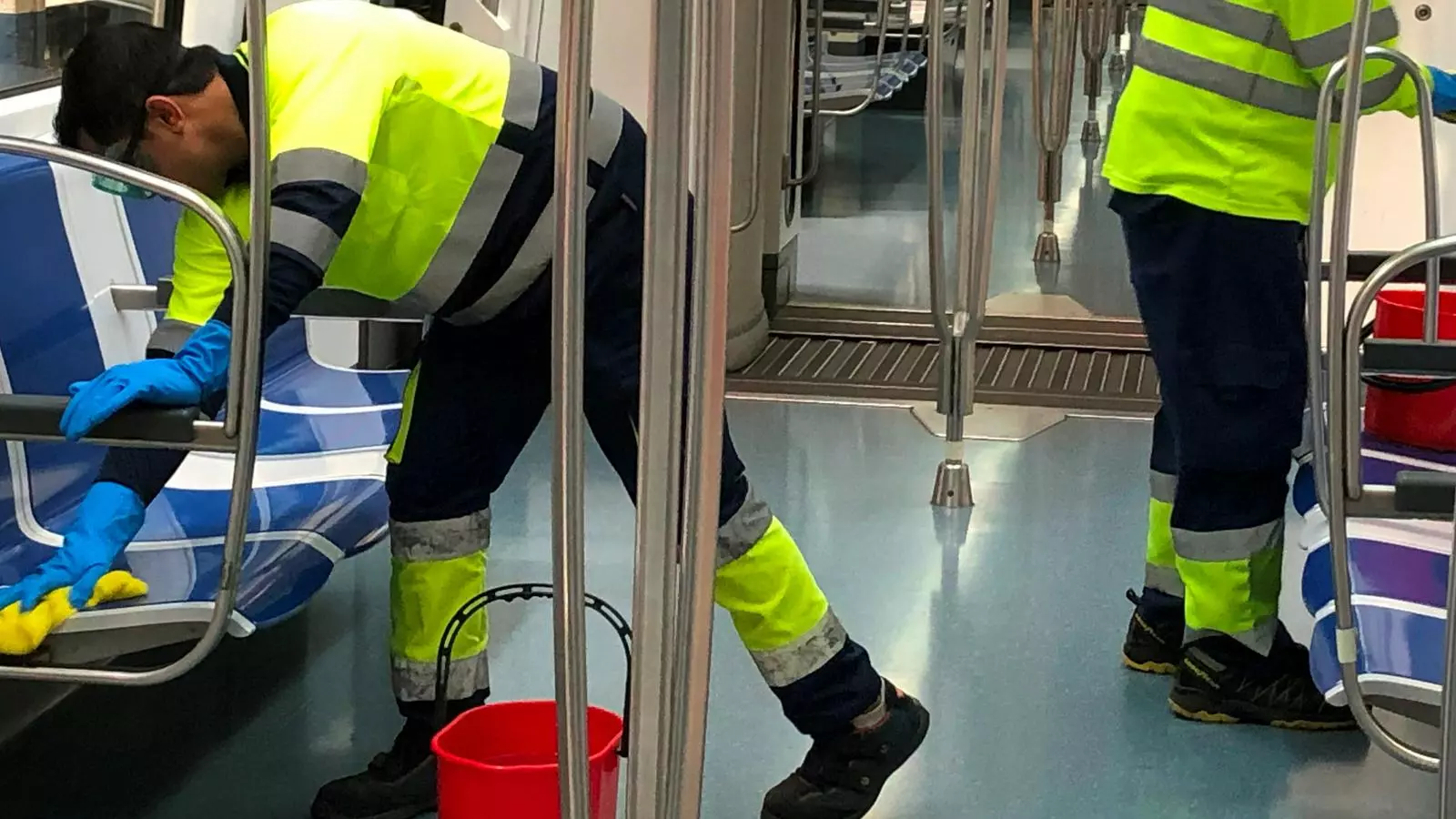 Dos operaris netegen l'interior d'un vagó de metro de TMB