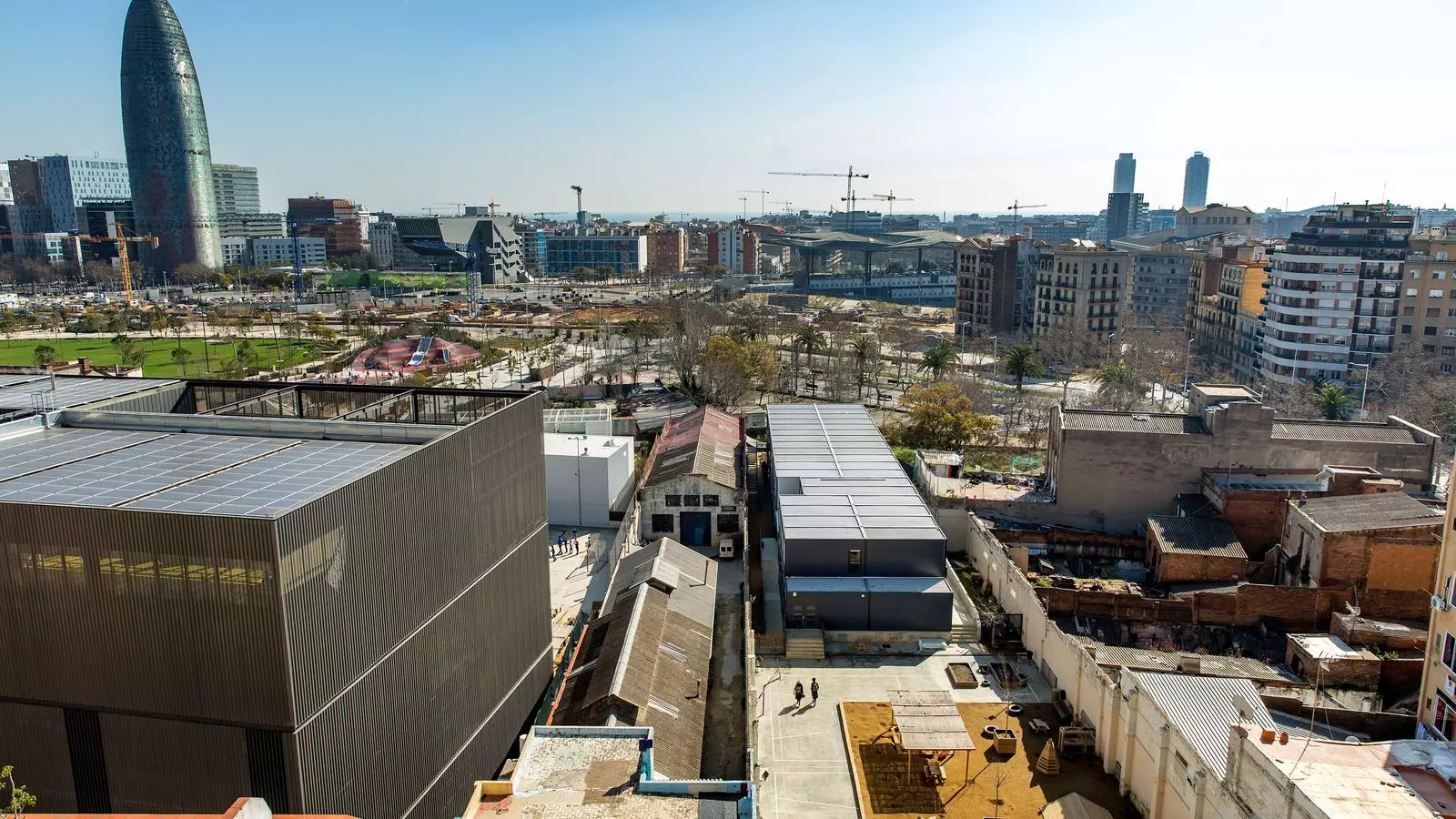 L'Escola dels Encants (esquerra) i l'Escola Gaia (dreta) separades per una nau industrial on el Consorci d'Educació ha trobat amiant a la teulada