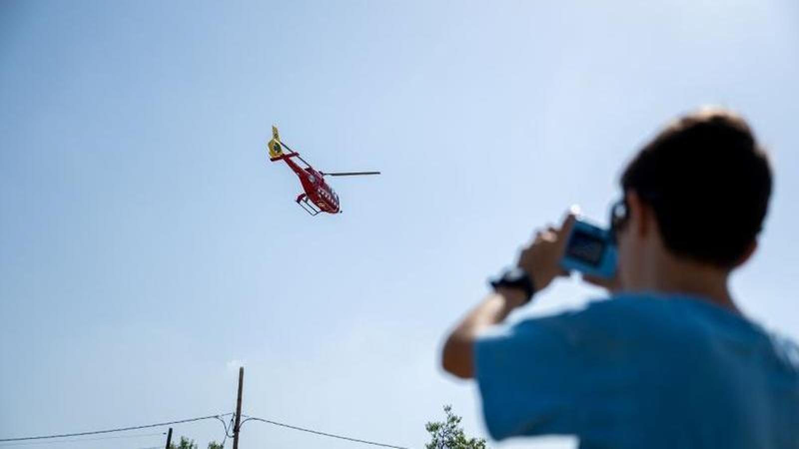 Un niño fotografía la salida de un helicóptero del centro de operaciones de los bomberos en el municipio de Sant Jaume dels Domenys.