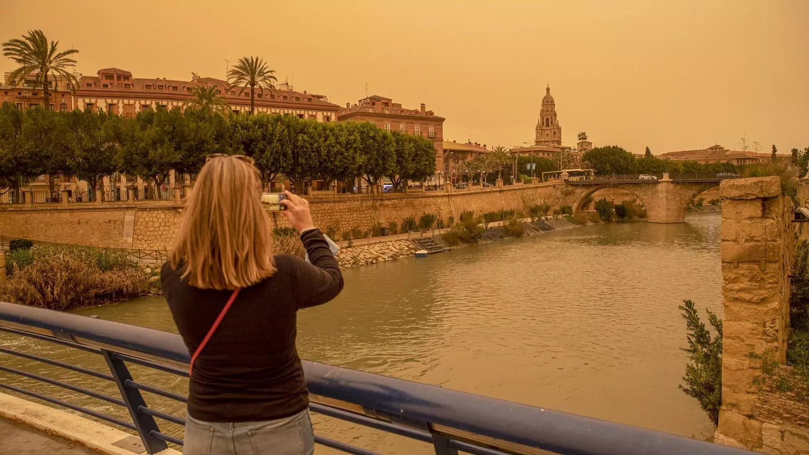 Una dona fa una fotografia amb el mòbil de l'aspecte que presentava la ciutat de Múrcia, amb un alt nombre de partícules i pols en suspensió que li dóna aquest color ataronjat al cel