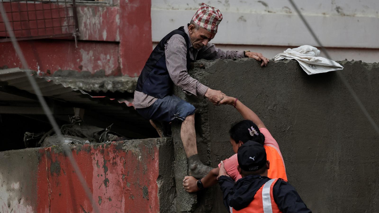 Rescue personnel help a man to exit from a damaged building after the deadly floods and landslides in Devighat, in Nepal.