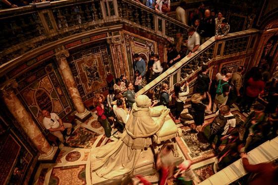Visitors in the crypt of the basilica of Santa Maria Major walking near a statue of Pope Pius IX.
