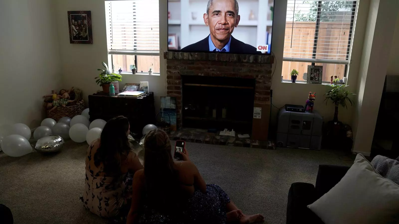 Dues de les noves graduades escoltant el discurs d'Obama per la televisió