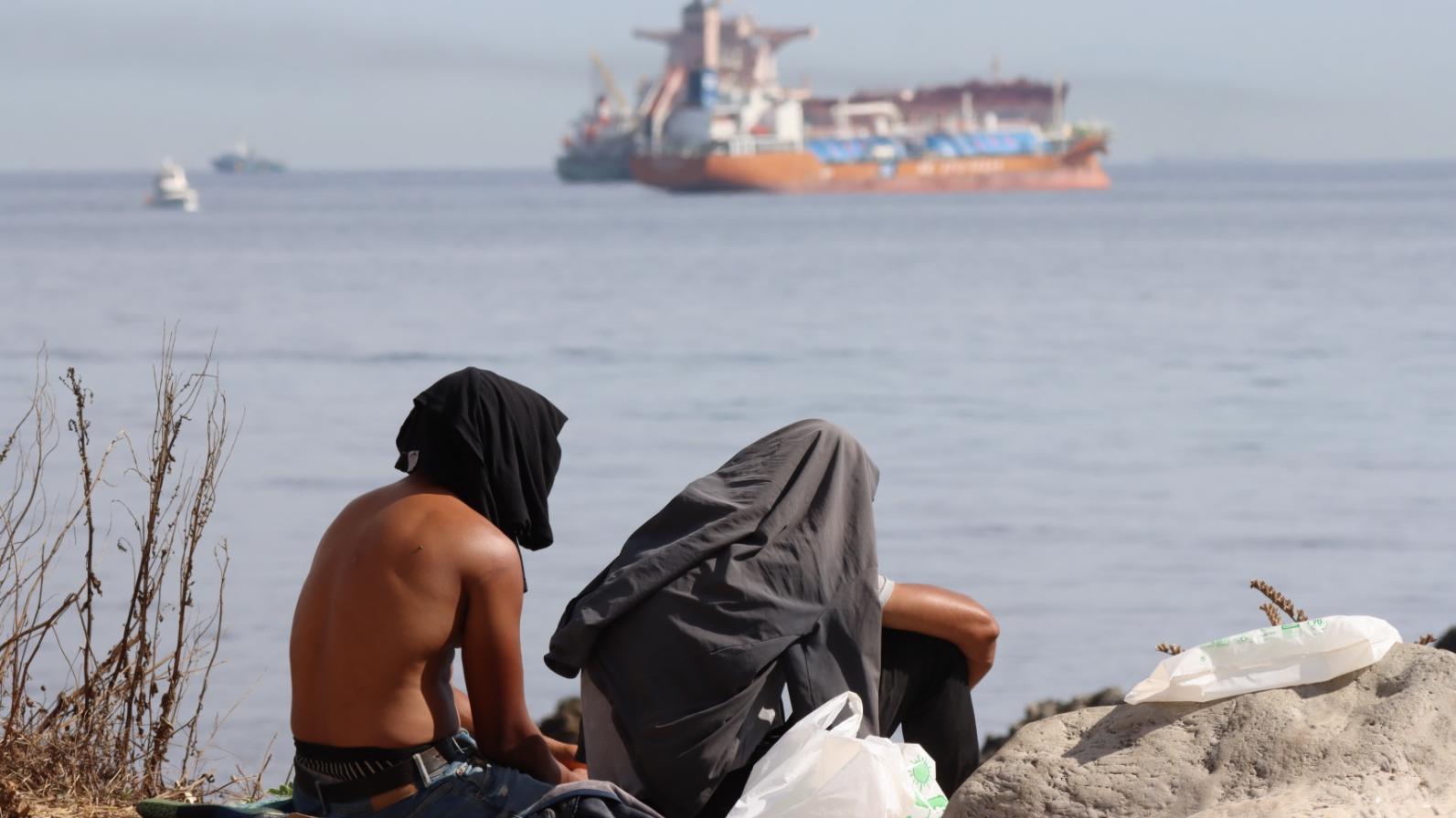 Dos migrantes en la playa de El Trampolín de Ceuta