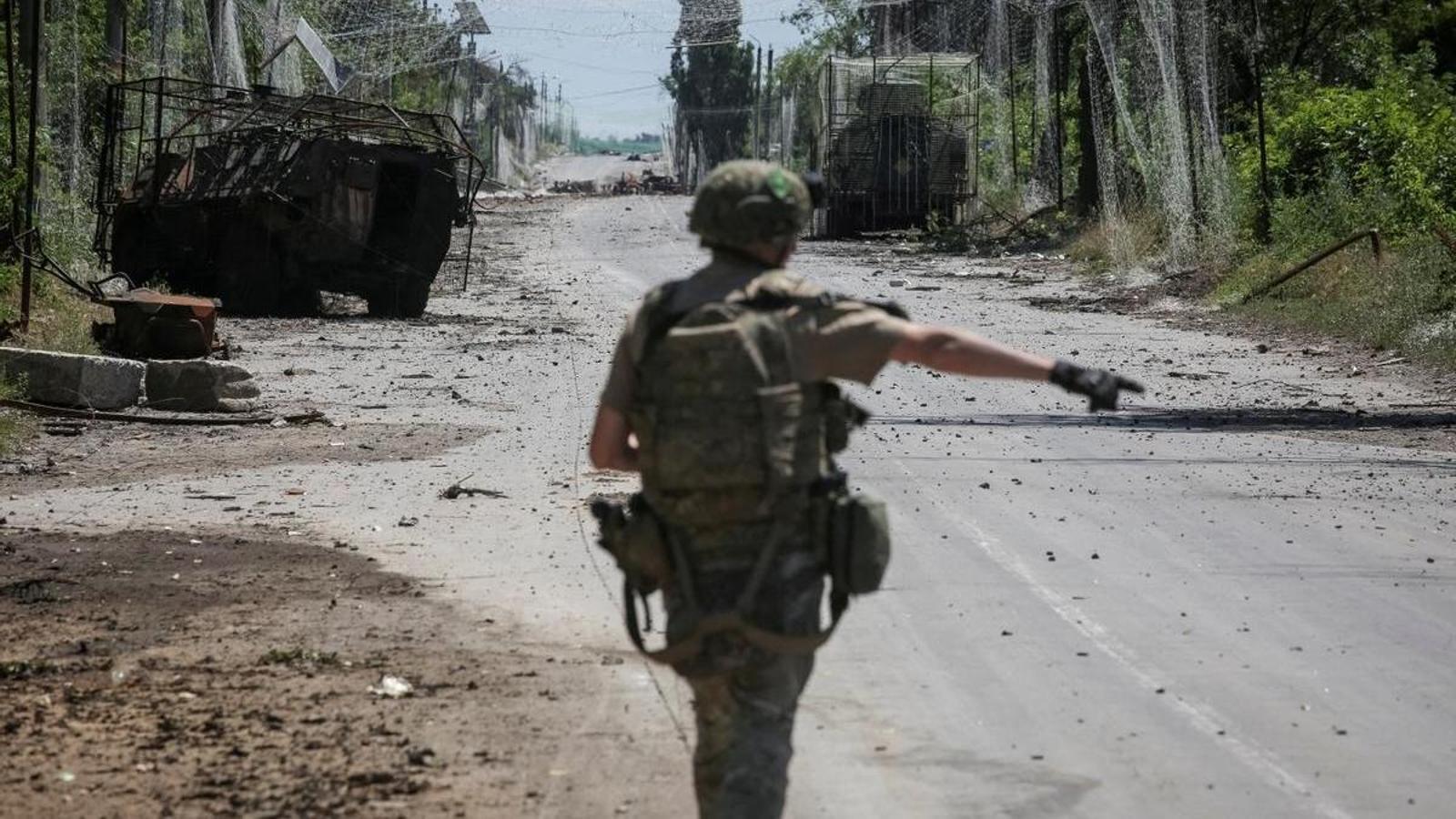 Un militar ucraniano camina por una carretera con redes antironas y vehículos militares destruidos, entre las ciudades de primera línea de Druzhkivka y Kostiantynivka, en la región de Donetsk.
