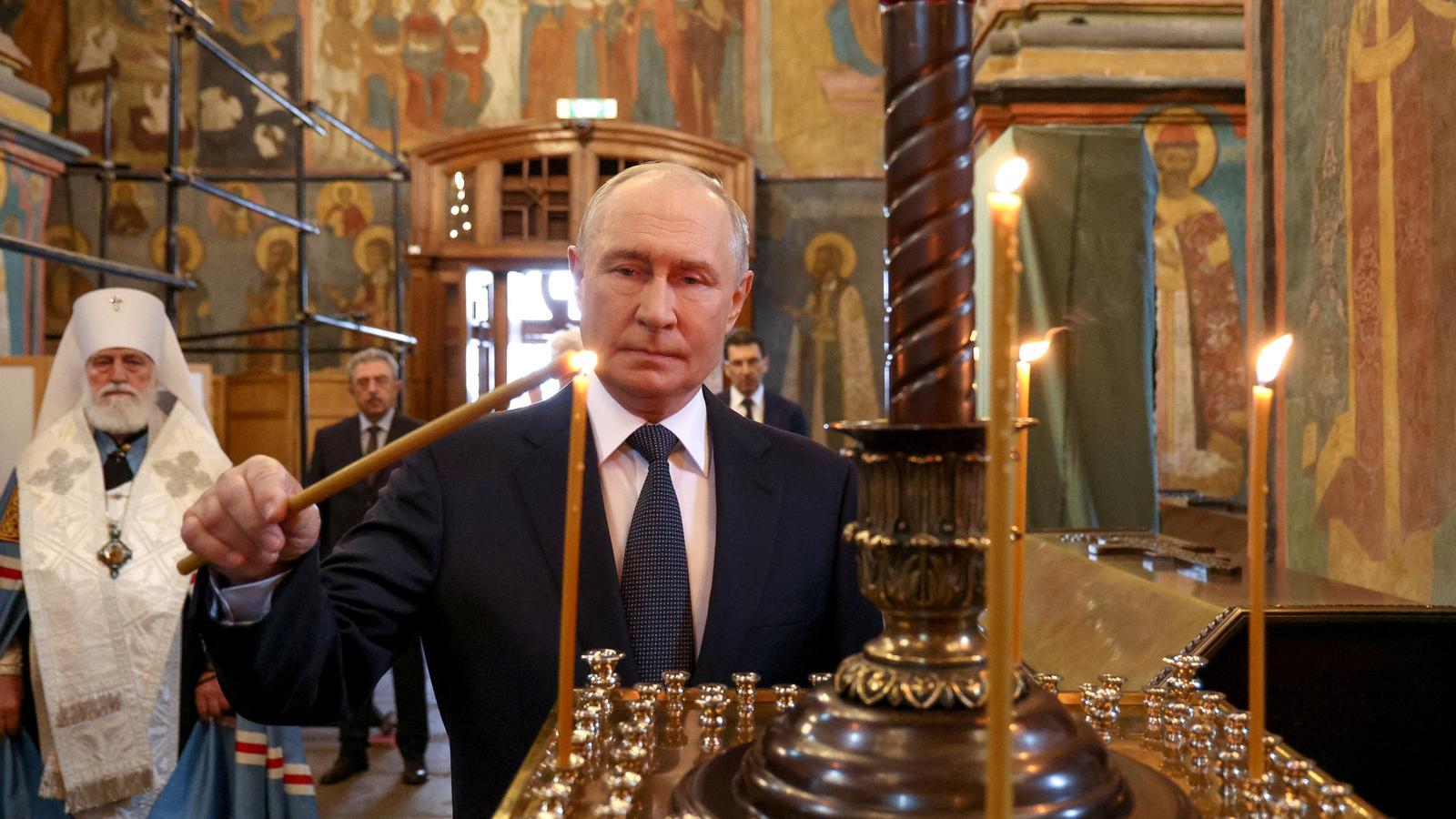 El presidente ruso Vladímir Putin enciende una vela en la catedral del Arcángel del Kremlin, en Moscú.
