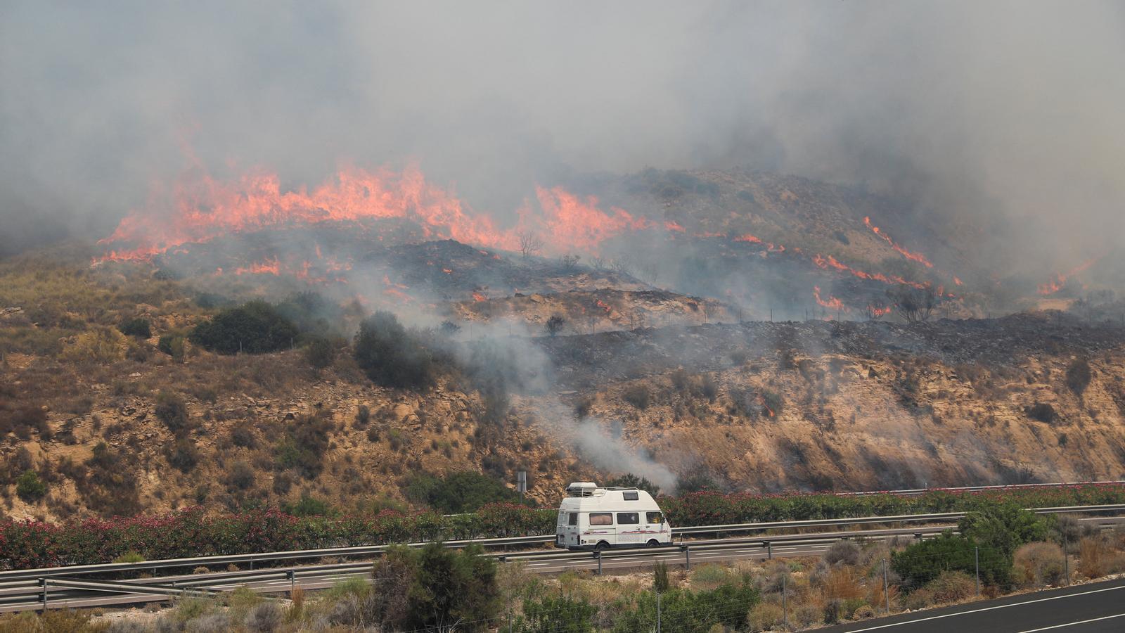 Una furgoneta circula por la autovía A-7 ante la proximidad del incendio forestal declarado en la zona de Los Gallardos (Almería).