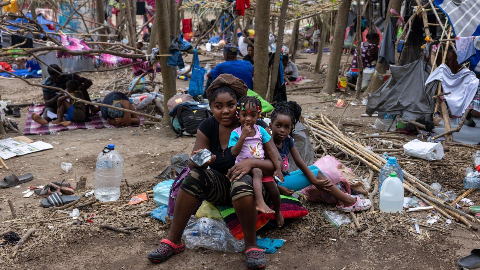 Membres de una familia haitiana  sientan fuera de viviendas improvisadas en un gran campamento de inmigrantes cerca de un puente internacional a la frontera entre Estados Unidos y México