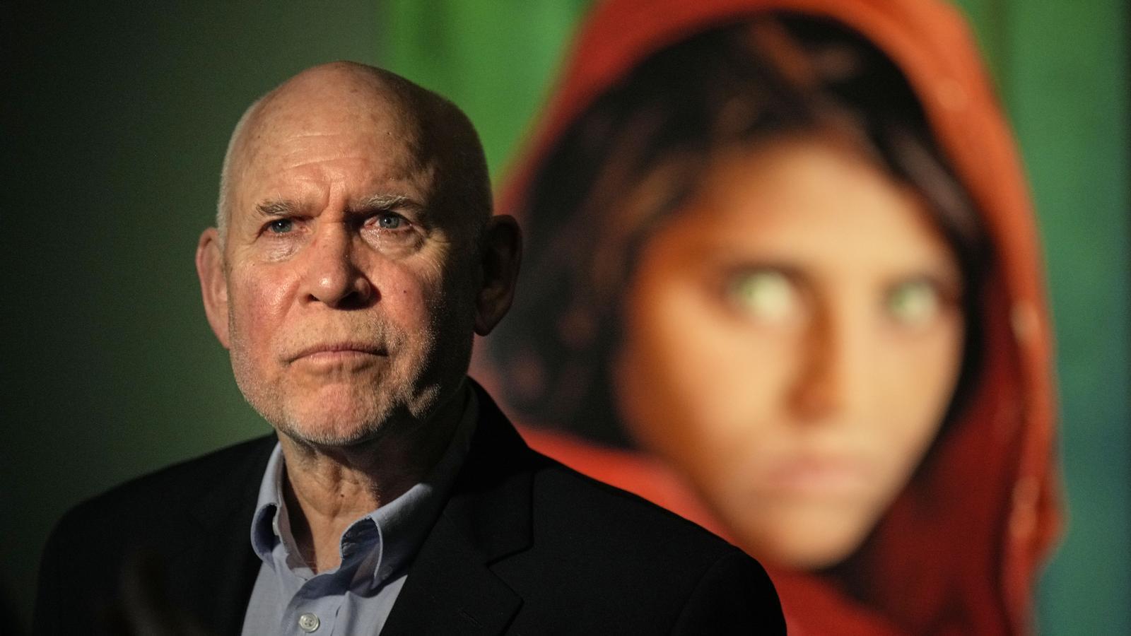 Steve McCurry at Palau Martorell with the portrait of Afghan girl Sharbat Gula in the background