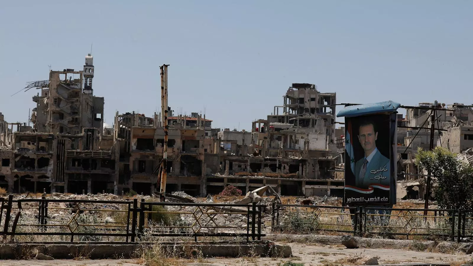 Un cartell electoral de Baixar al-Assad davant d’edificis en ruïnes a Homs.