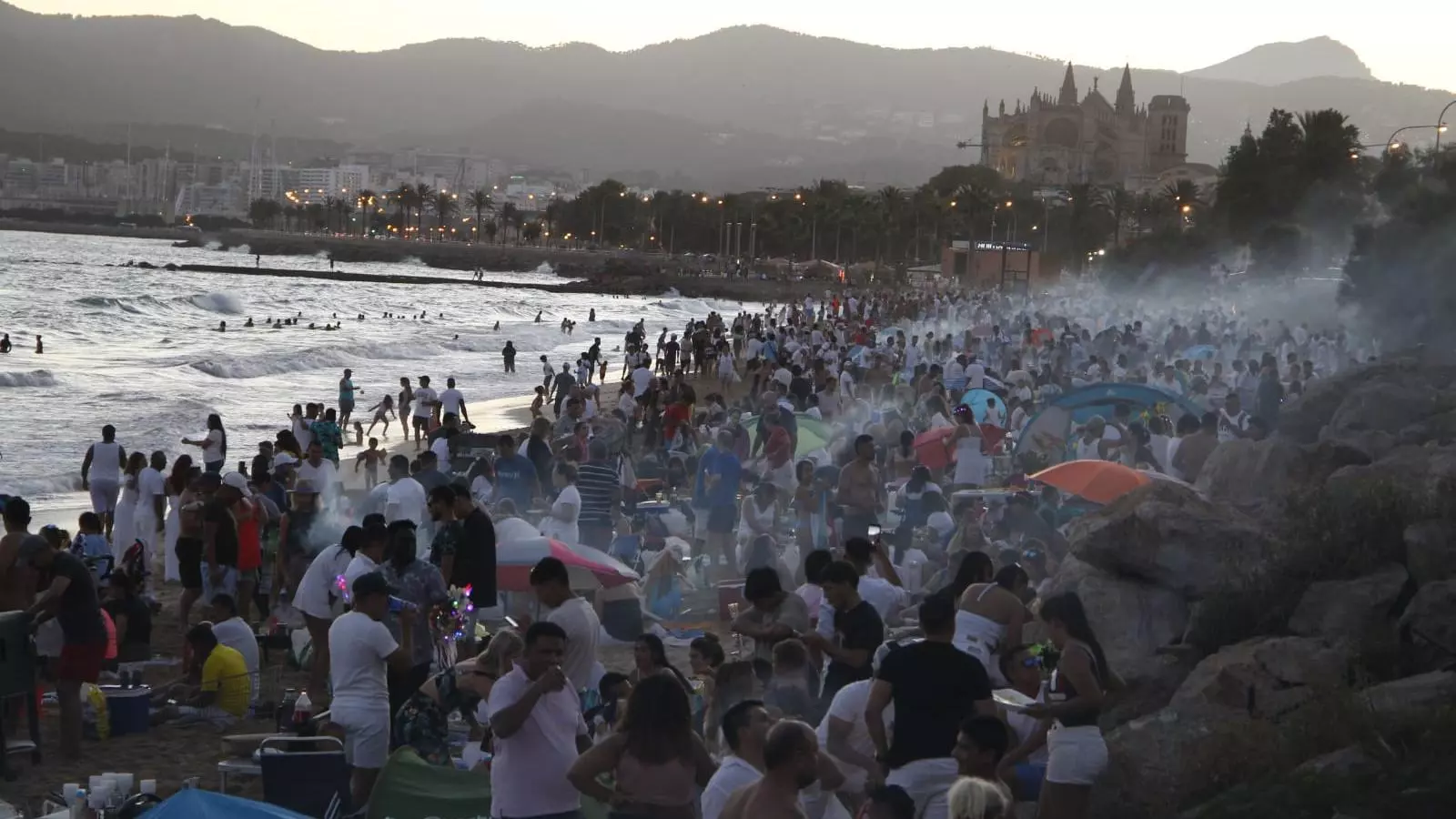 La gent a la platja fent festa i sopant.