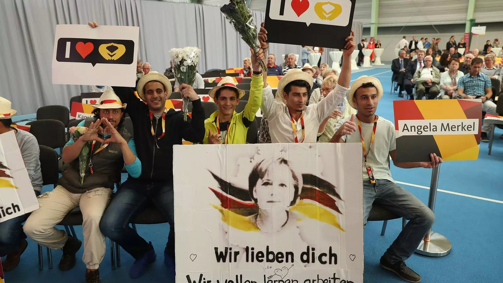 Refugiats sirians amb cartells elogiant Merkel, on es llegeix "T'estimem, volem estudiar, treballar i viure", en un acte de la CDU el 2017.