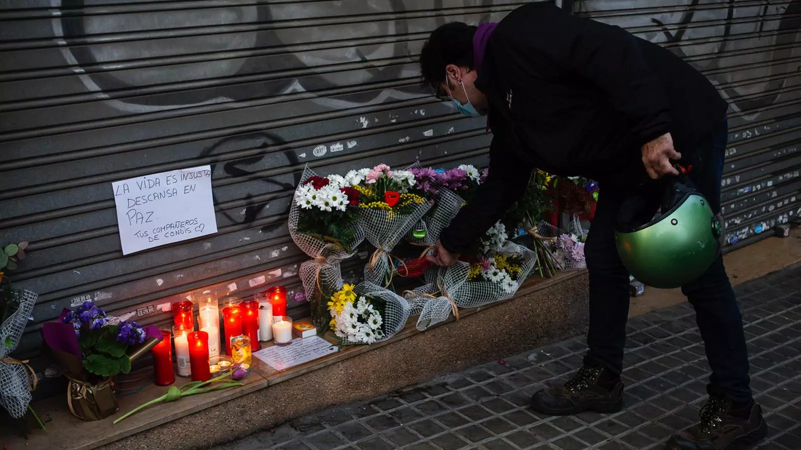 Una persona deixant un ram de flors davant les persianes del basar xinès