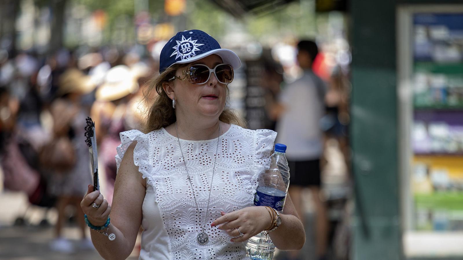 A woman fanning herself in Barcelona because of the heat.