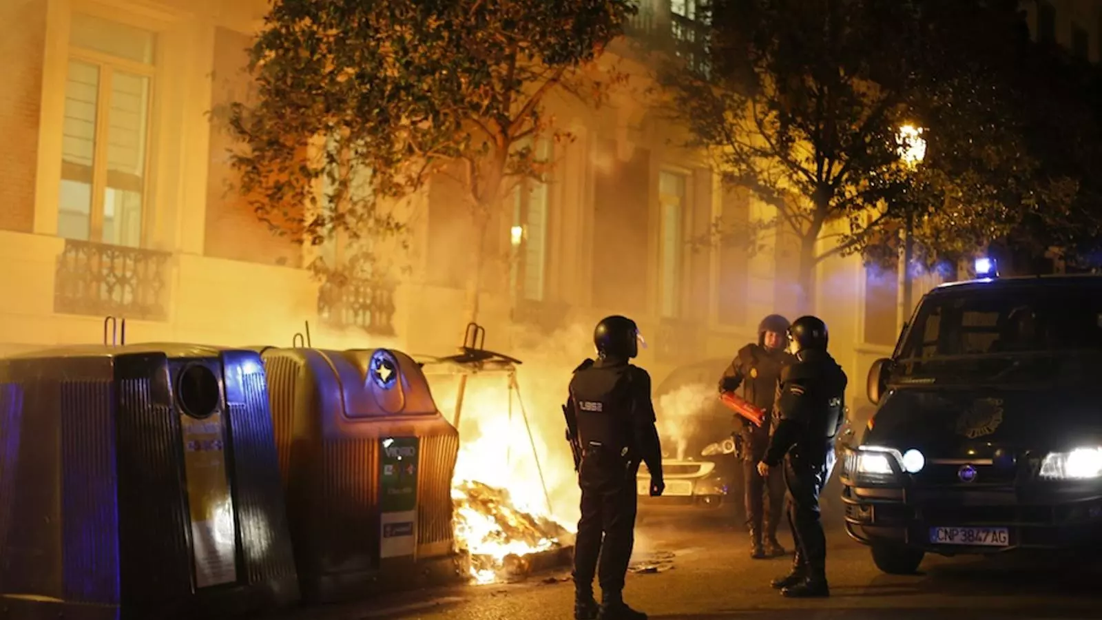 Els agents antiavalots, al costat d'un contenidor en flames