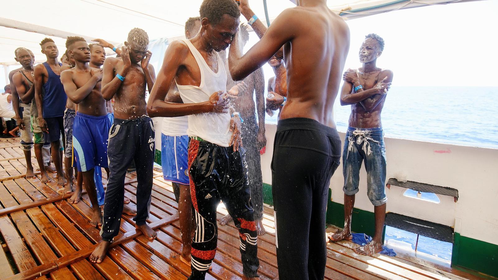 Un grup de migrants es dutxa a bord del vaixell d'Open Arms.