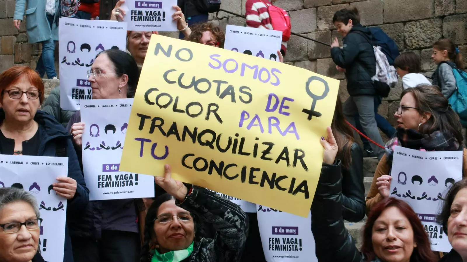 Dues dones amb cartells reivindicatius en la presentació de la vaga feminista a la plaça del Rei de Barcelona