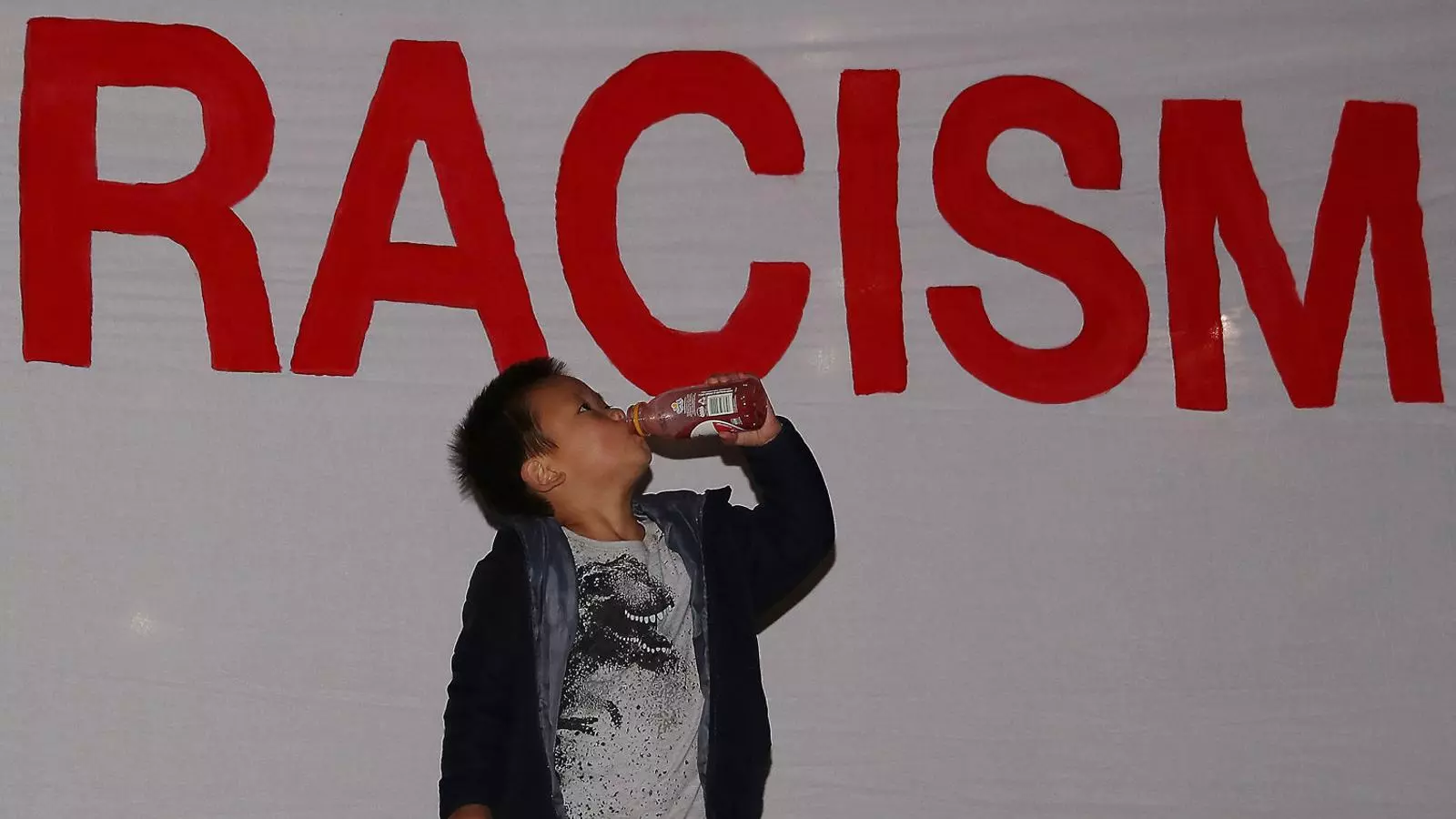 Un nen davant un cartell antiracista d’un grup d’activistes a Nova Zelanda. Com els científics, els artistes fa temps que es mobilitzem contra la xenofòbia.