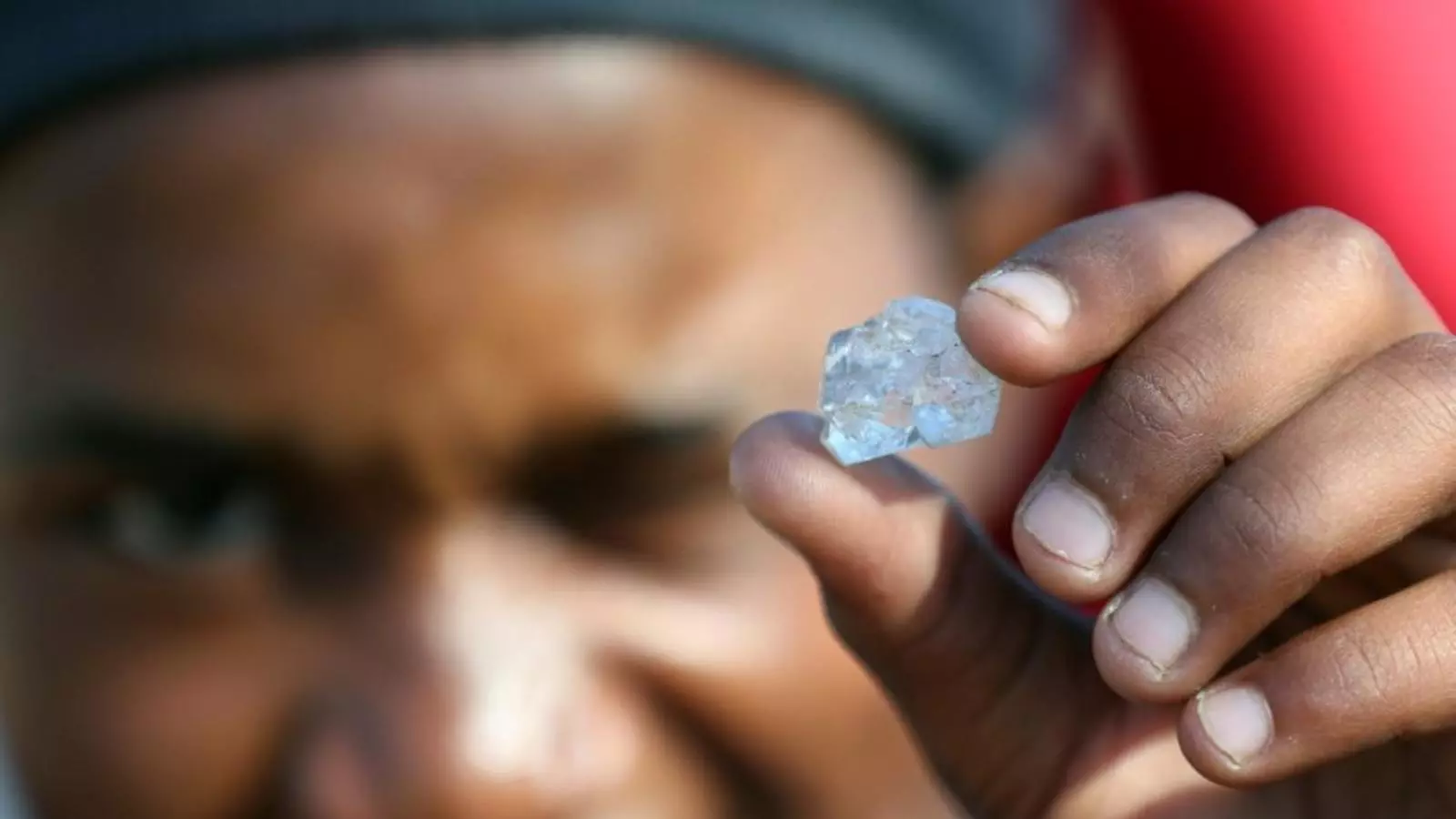 Un hombre muestra una de las piedras brillantes sin identificar que ha encontrado excavando