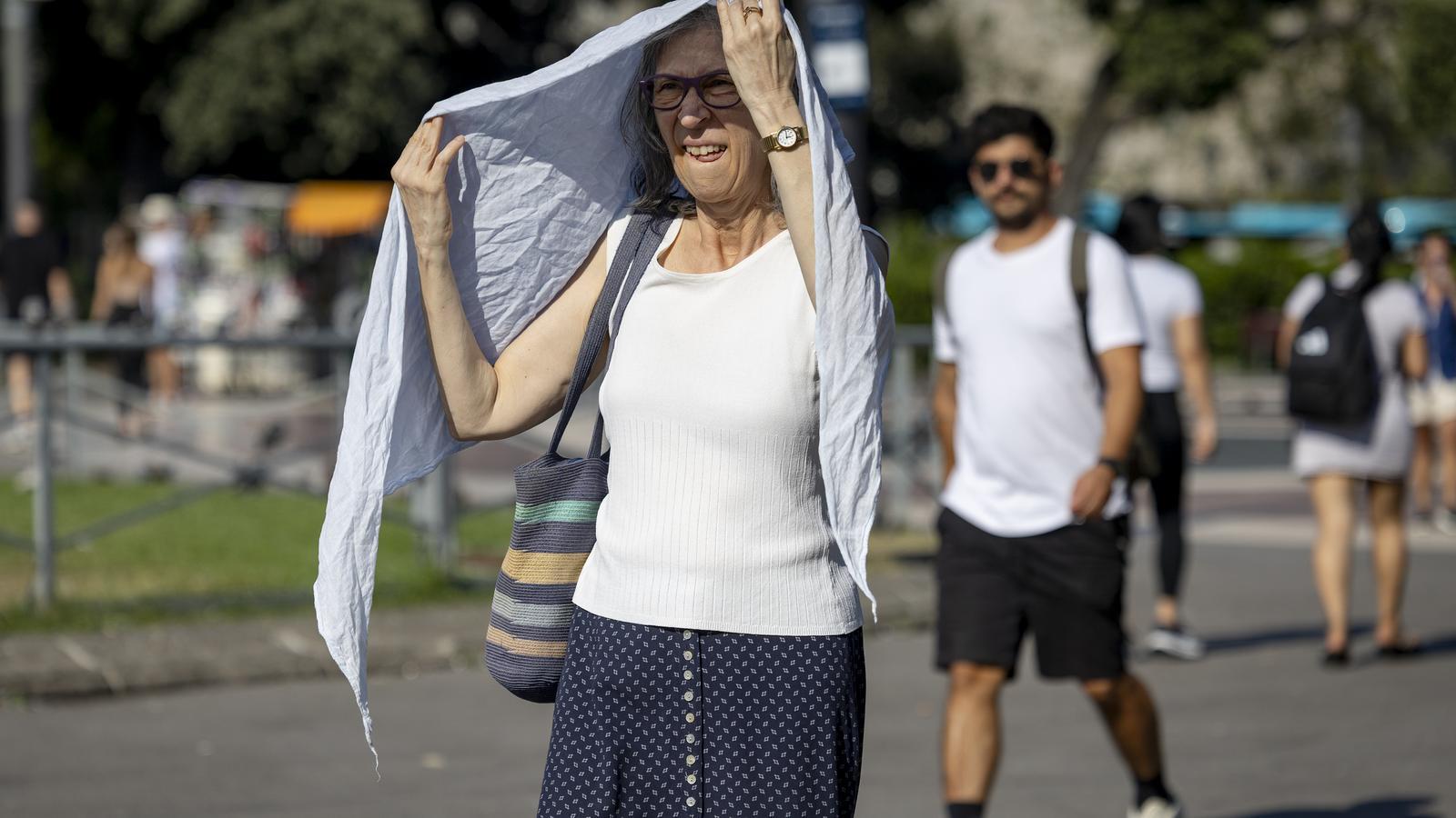 Una mujer protegiéndose del sol en la plaza Catalunya de Barcelona.