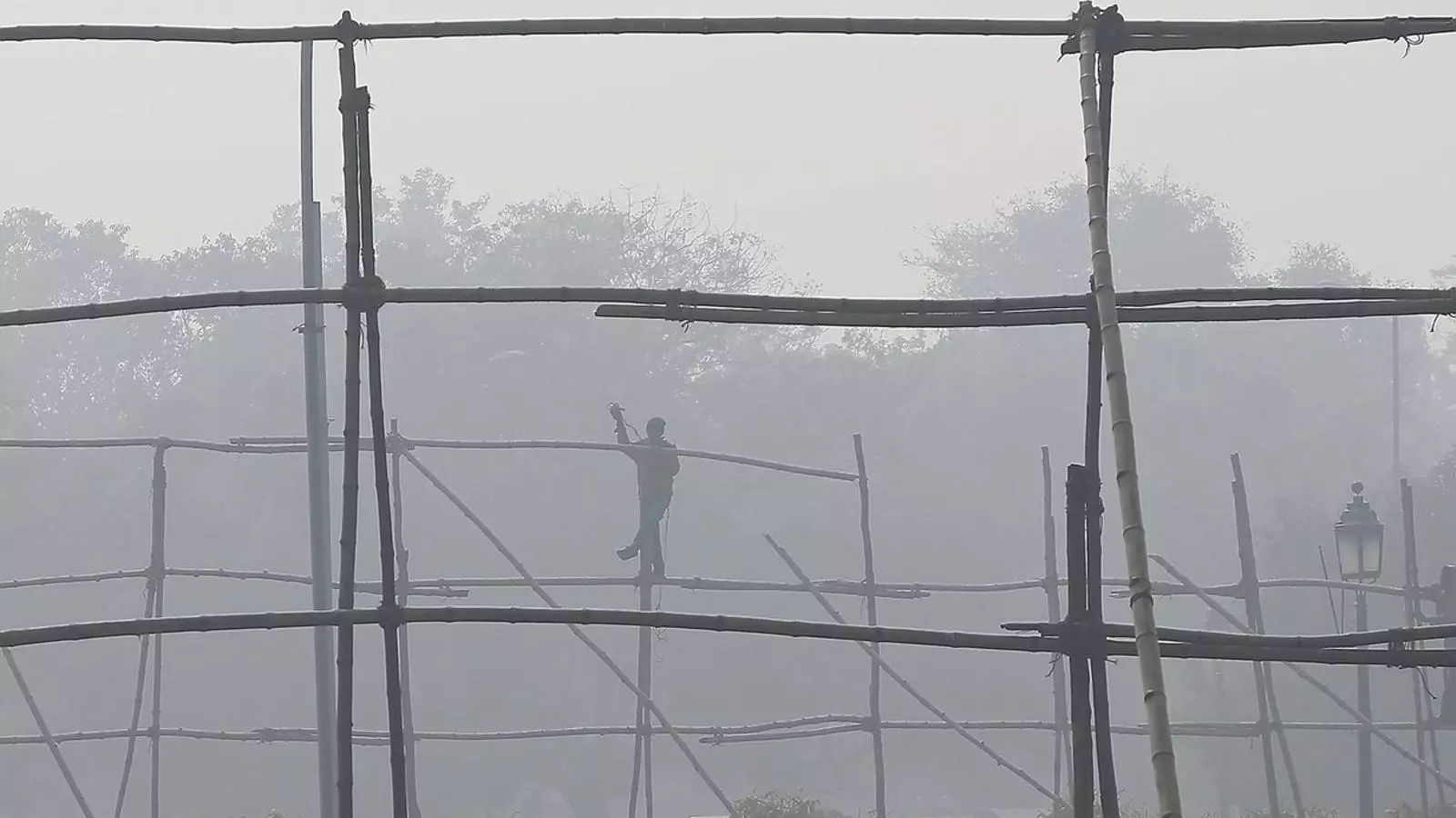 Un treballador desmuntant bastides Enmig de la contaminació a Nova Delhi, a l’Índia.