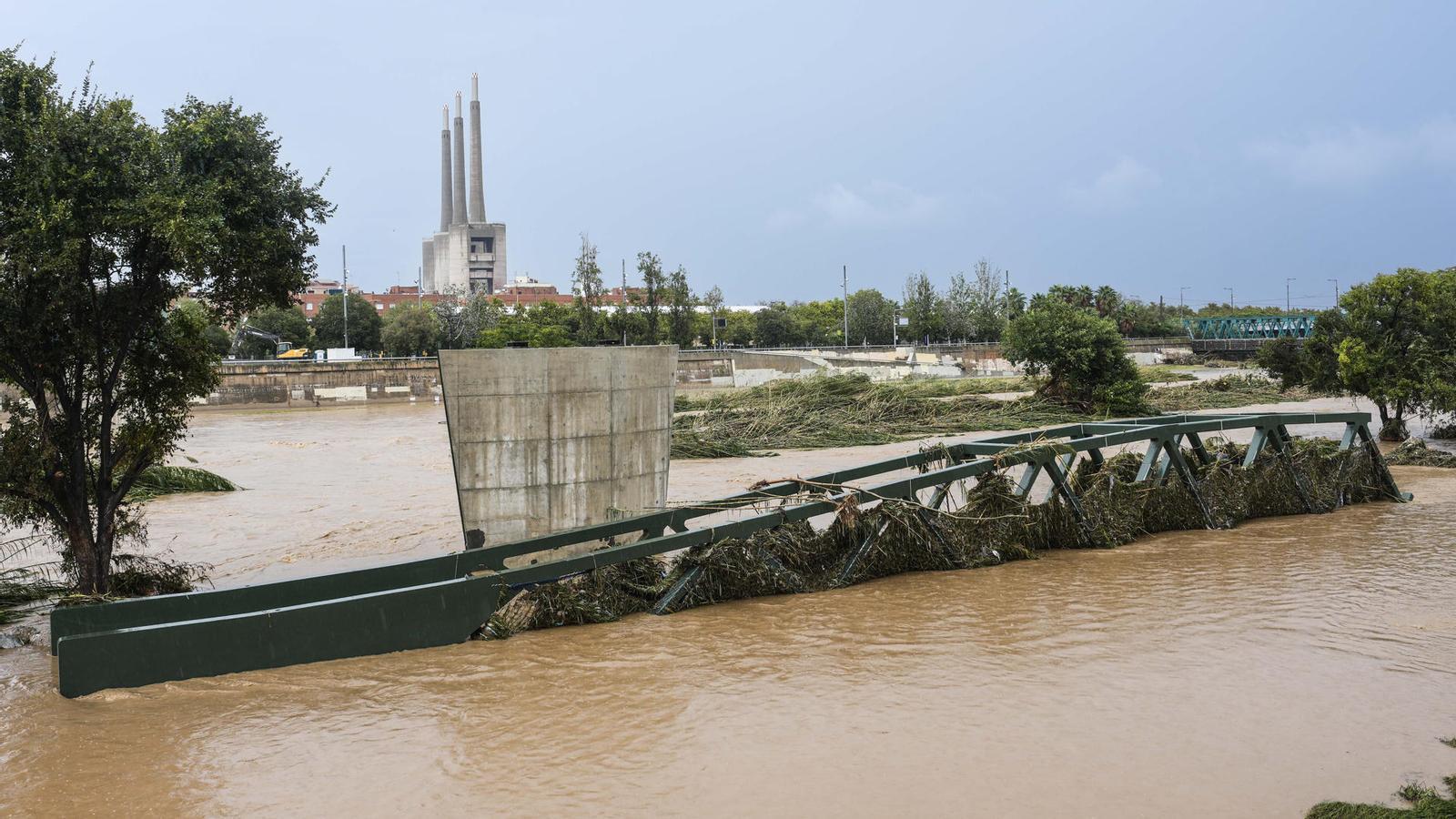El río Besòs desbordado por el temporal el pasado lunes y las Tres Chimeneas al fondo.
