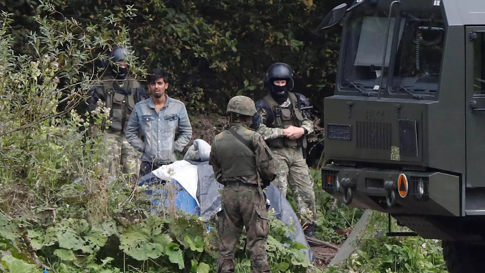 Un dels migrants afganesos que han quedat atrapats a la frontera, entre soldats polonesos (en primer pla) i bielorussos (al fons)