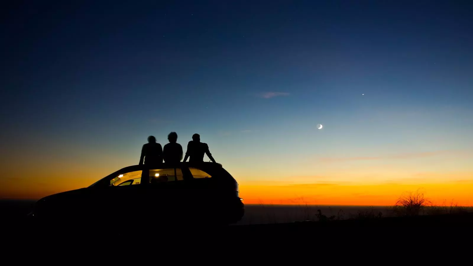 Tres joves contemplant una posta de sol