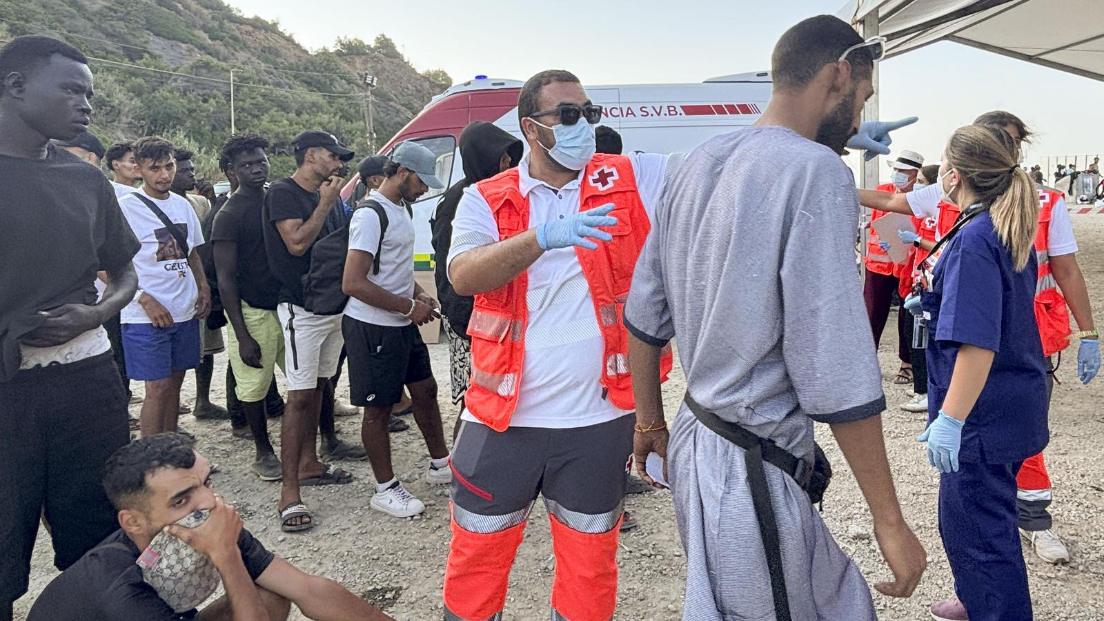 Red Cross personnel attending to the migrated people who have settled on the Trampolín beach in Ceuta.