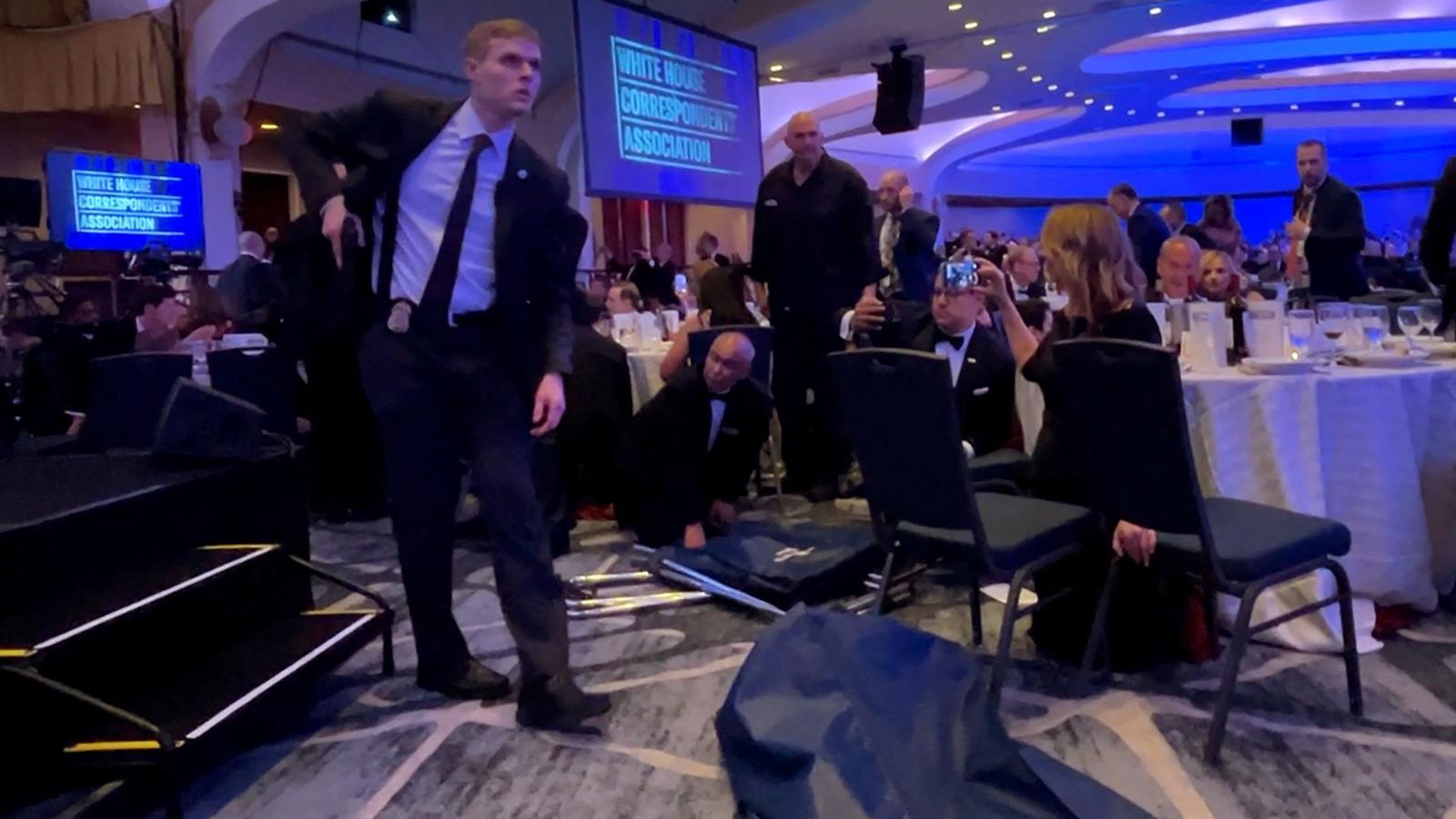Un agente del Servicio Secreto de los EE. UU. desenfunda su arma después de la evacuación del presidente Donald Trump durante la cena de corresponsales en la Casa Blanca.