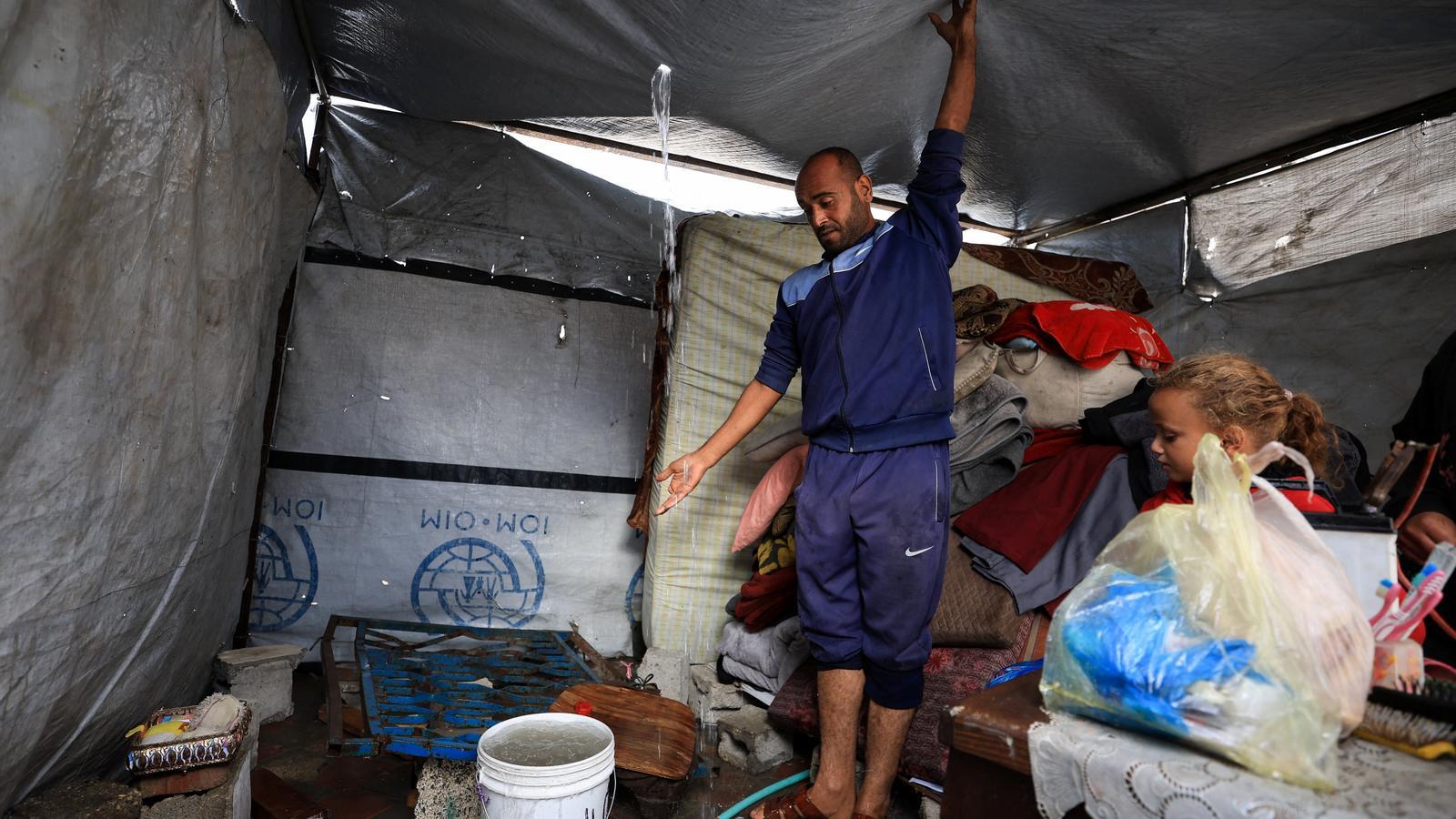 Un palestino intenta mantener de pie la tienda de campaña donde vive con su familia en Ciudad de Gaza, pese a las fuertes lluvias.