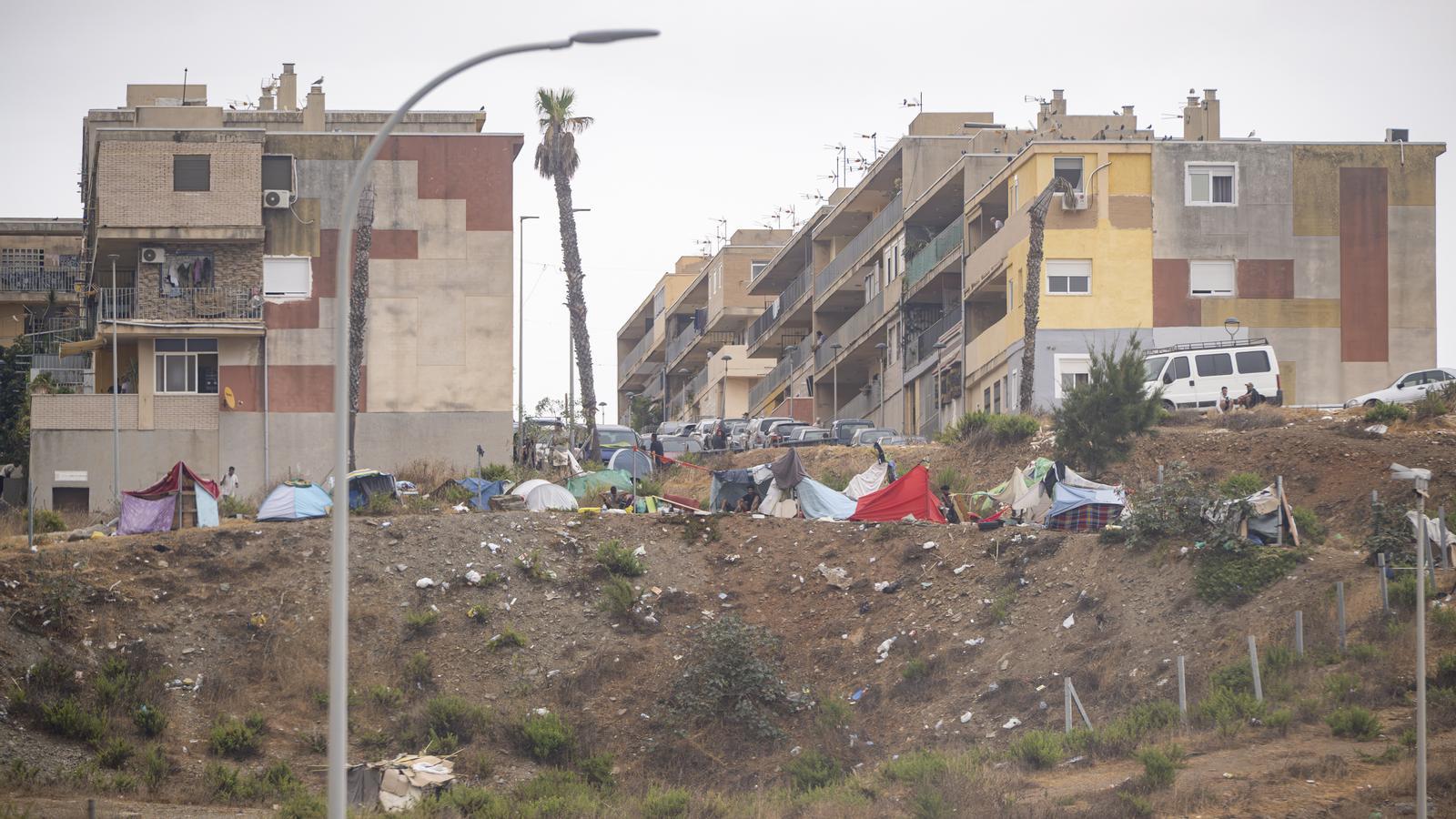 Diversos migrantes se protegen de la lluvia con lonas en Ceuta, donde la policía ha reforzado la vigilancia.