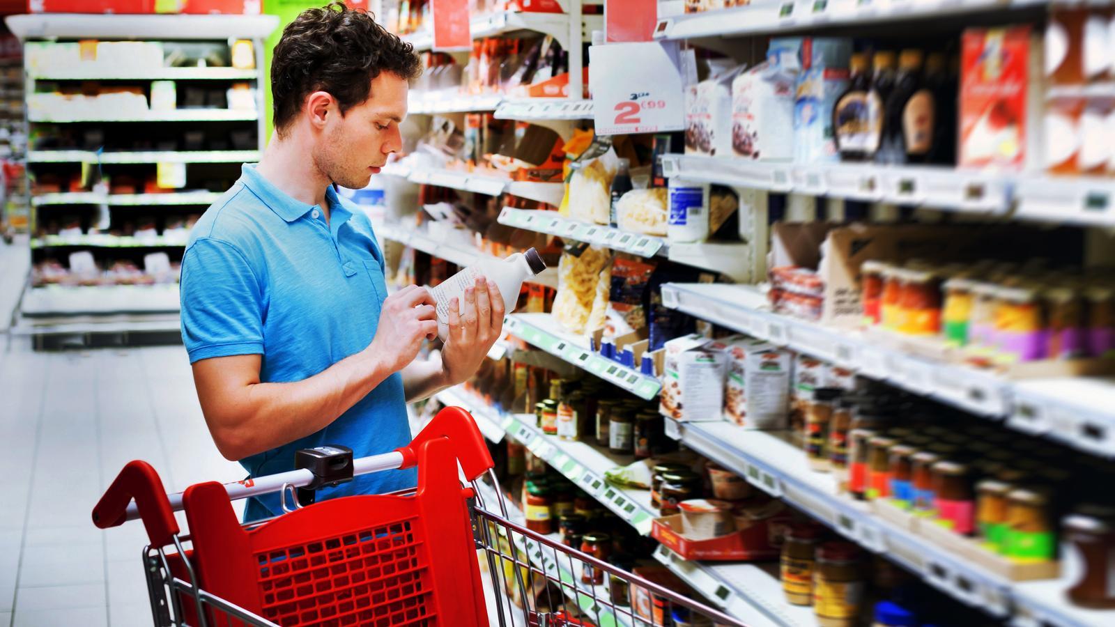 A man looking at the label of a product in a supermarket.