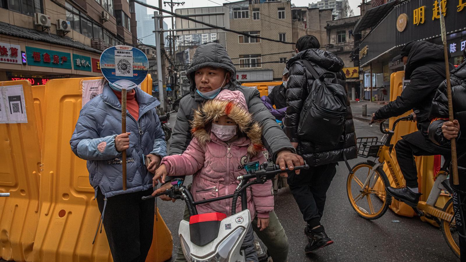 una familia utilitza un codi de barres per passar un control, a la zona de Wuhan, a la Xina