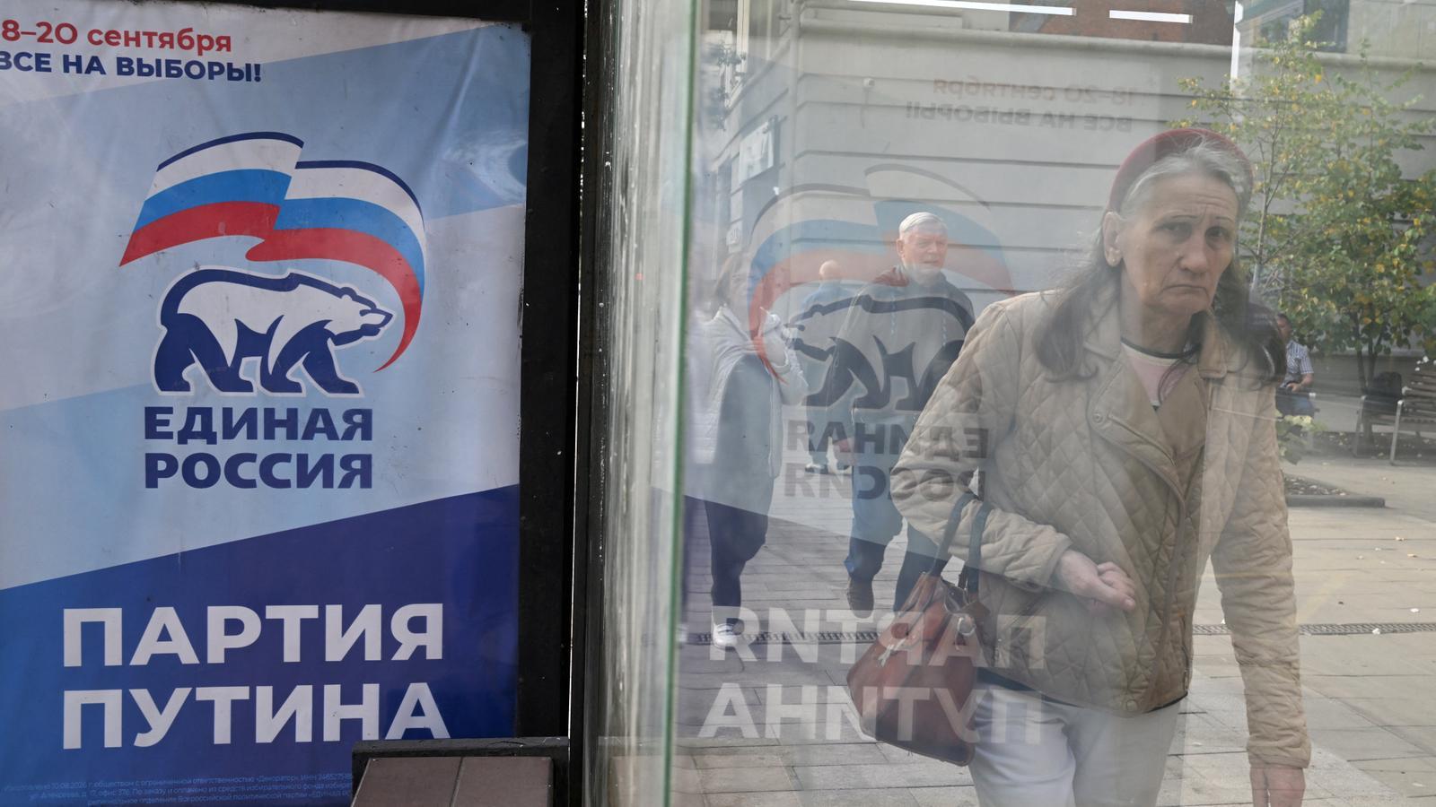 A woman walks next to a United Russia sign in the Russian city of Krasnoyarsk.
