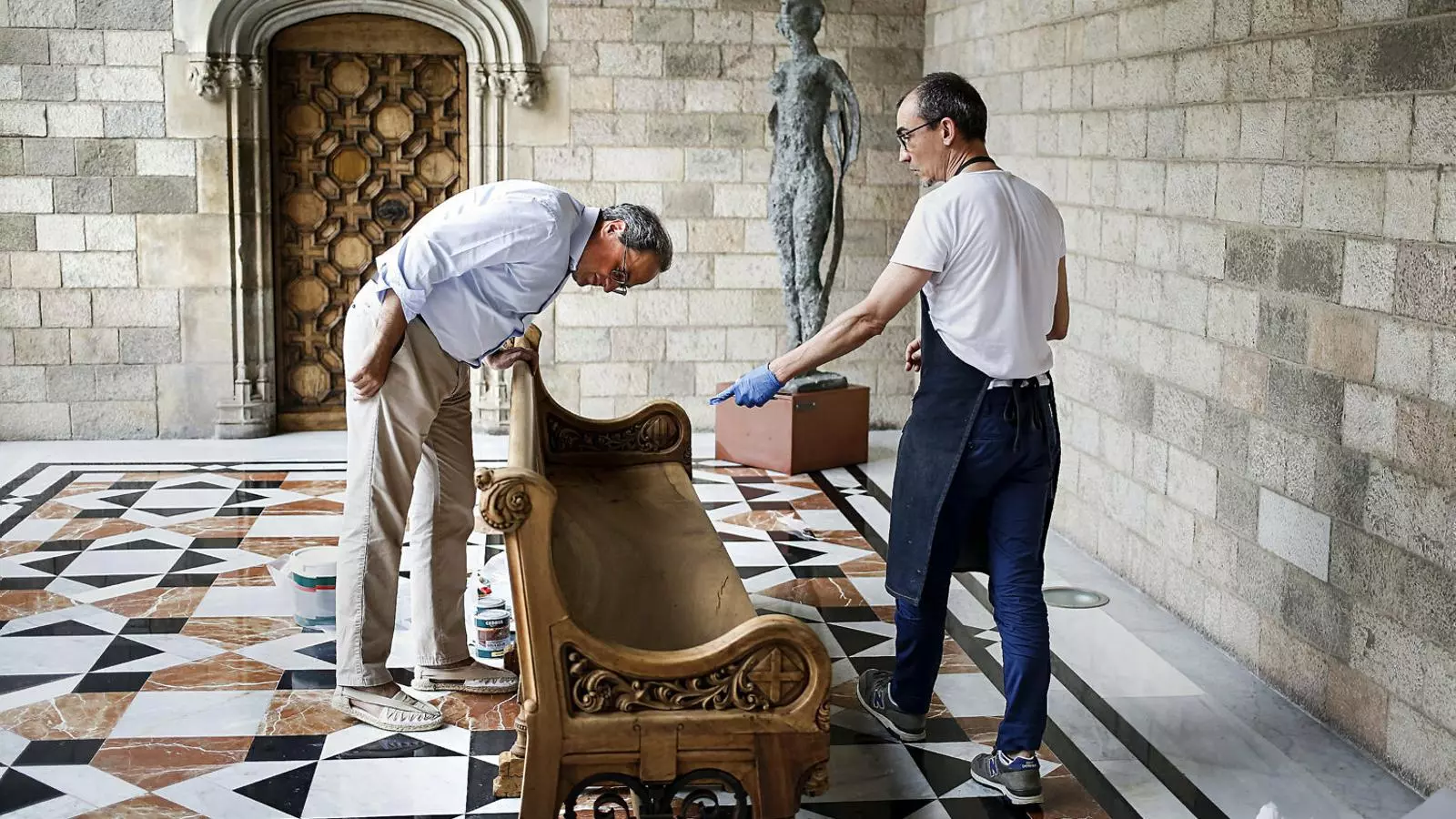 Quim Torra observant un banc de fusta al Palau de la Generalitat.