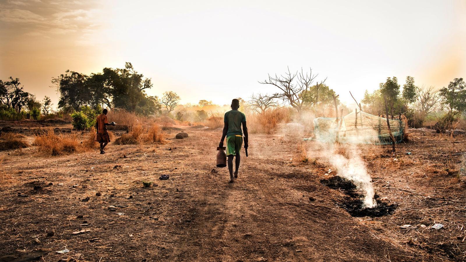 Dos mineros dirigiéndose a la explotación de oro artesanal de Tomboronkoto, en el Senegal, a primera hora de la mañana con el material que necesitan para trabajar.