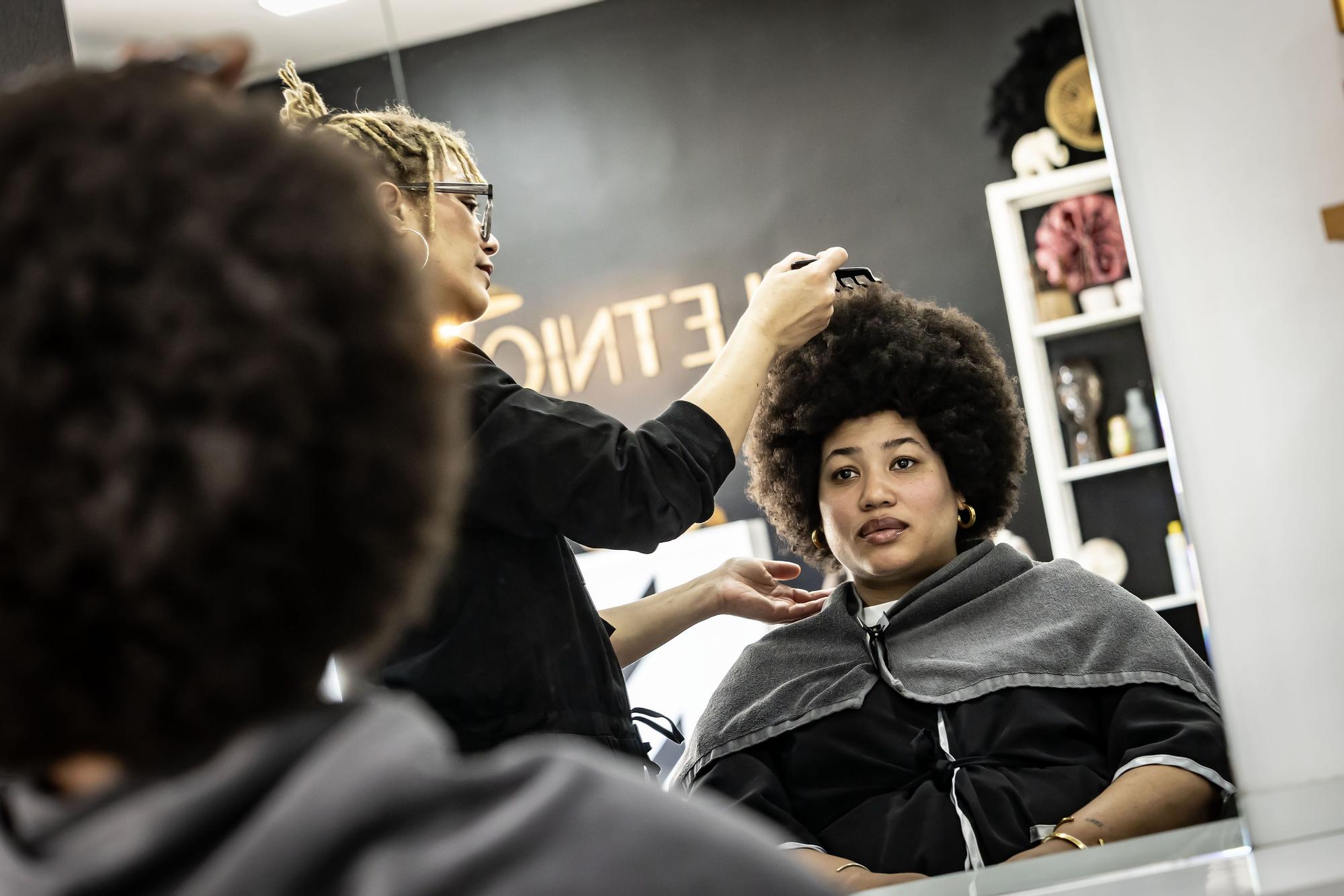 Isabel se mira al espejo mientras Tamy la peina en la peluquería Iletnic, en Barcelona.